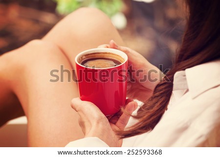 Morning coffee. Woman holds a red coffee cup