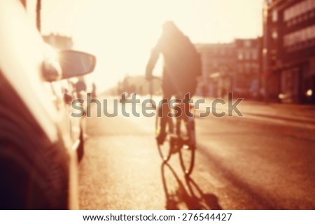 City commuters. High key blurred image of people riding a bike in the street. Unrecognizable faces.