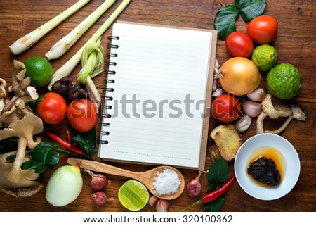recipe book with fresh herbs south asia and spices on wooden background, hot and sour soup, thai food.