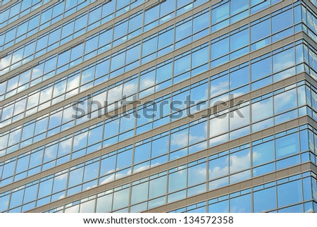 An office building\'s glass wall mirroring cloud and blue sky Beijing, China