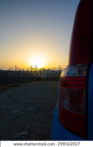 Brake lights of the car against the sunset and hills