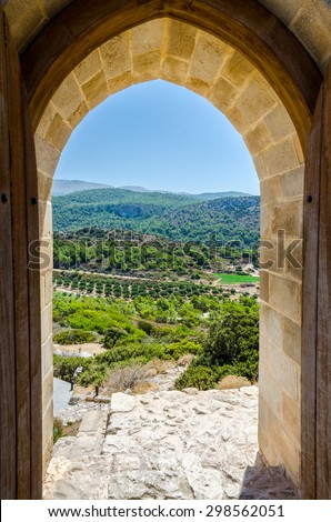 View of the hills with green trees through the arch on a bright sunny day