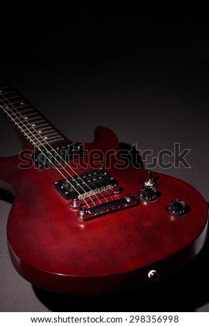 Electric guitar mahogany, dark background, vertical composition, a stringed musical instrument, electronic control bodies, six-string guitar, tuning and adjustment.