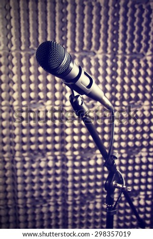 Modern microphone on a stand, recording studio, microphone\
 picture, sound wall, microphone stand, mesh wire, close-up shot, vertical image, images in dark colors.