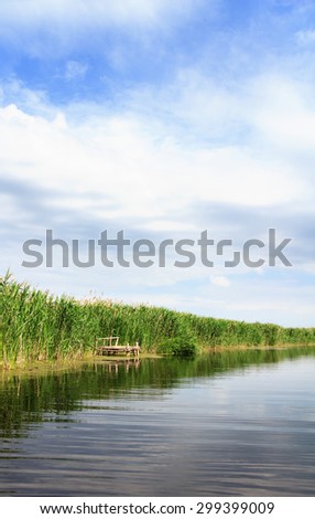 River landscape, clouds in the blue sky, the waves on the water, river, green tourism, travel along the river, boating, summer sunny day after the storm, a harbor for ships, aquatic vegetation.