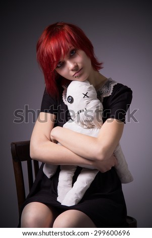 Red-haired girl, dress with lace collar, rag doll sitting on a chair, hugging a doll, blue eyes, vintage image, vertical photo, gradient background.