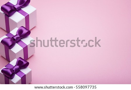 Gifts in a beautiful package, bow from satin ribbon, a few boxes with gifts standing in a row, the attributes of the festive mood, the gift set on a pink background
