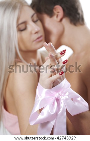 Young couple holding hands and kissing, hands connected by a bow in focus