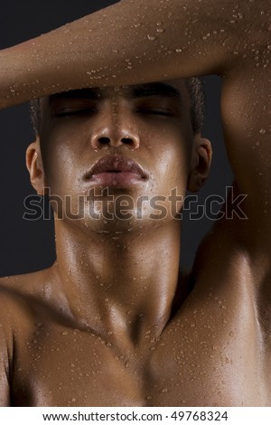 Drops of the water on naked body of a young man on black background.
