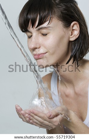 Happy beautiful woman wash her face with pure water