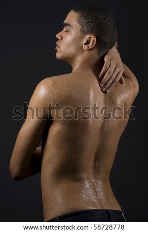 Drops of the water on the body of a young man on black background.