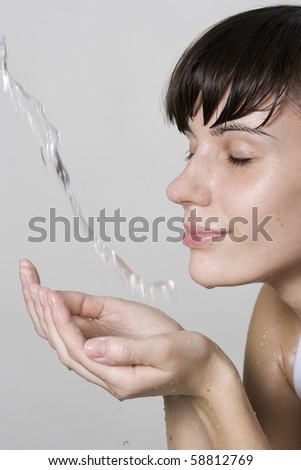 Happy beautiful woman wash her face with pure water