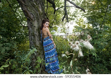 Portrait of a beautiful young woman wearing blue dress in the forest