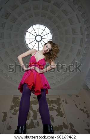 Fashion model in bright pink dress posing in old house