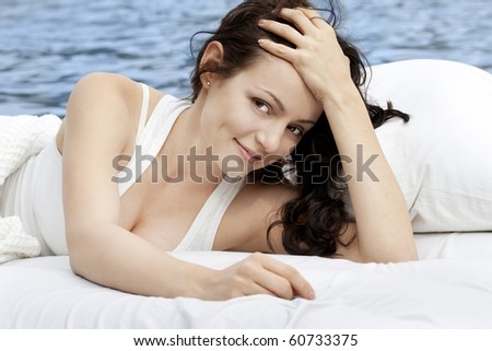 Beautiful young woman lying on the white bed in the sea