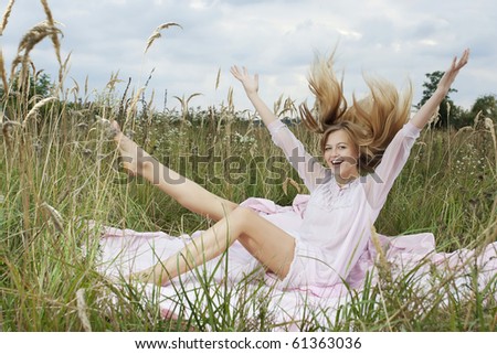 Portrait of a woman awakening on a pink sheet in a green field