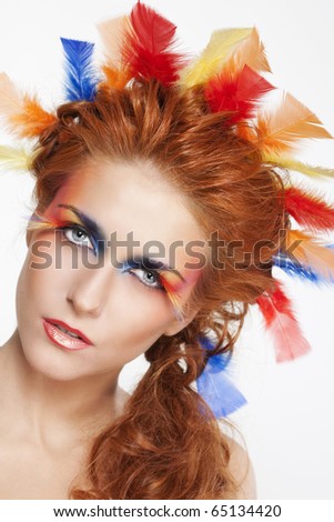 woman with face framed in feathers with bright makeup and long faux eye makeup with feathers. woman with face framed in feathers with bright makeup and long faux