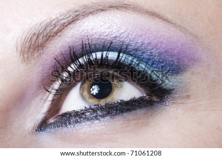 Macro shot of woman eye with violet and blue bright make-up