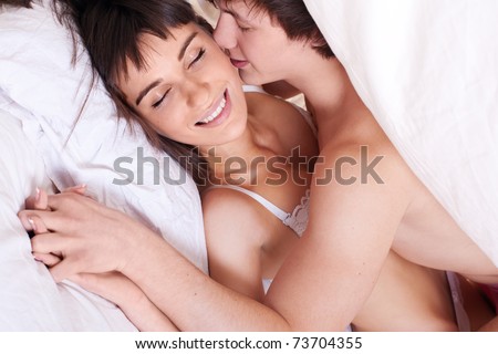 Young sexy couple making love in bed under the blanket