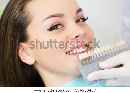 Close up portrait of Young women in dentist chair, Check and select the color of the teeth. Dentist makes the process of treatment in dental clinic office.Dentist
