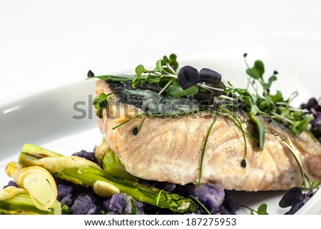 Salmon fillet on white wine sauce, served with asparagus baked in puff pastry and purple potatoes