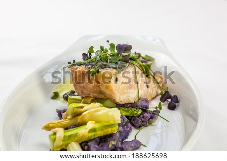 Salmon filet on white wine sauce, served with asparagus baked in puff pastry and purple potatoes