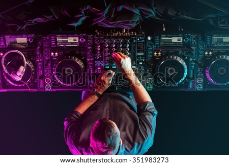 Charismatic disc jockey at the turntable. DJ plays on the best, famous CD players at nightclub during party.