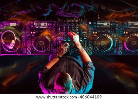 Charismatic disc jockey at the turntable. He plays on the best, famous CD players at nightclub during party. Party EDM concept.