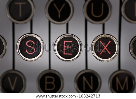 Close up of old typewriter keyboard with scratched chrome keys with black centers and white letters. Lighting and focus are centered on for keys spelling out \
