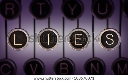 Close up of old typewriter keyboard with scratched chrome keys that spell out LIES. Lighting and focus are centered on LIES.