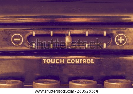 Close up of vintage typewriter front panel with touch control lever and the tops of four keys in muted warm purple and gold hues
