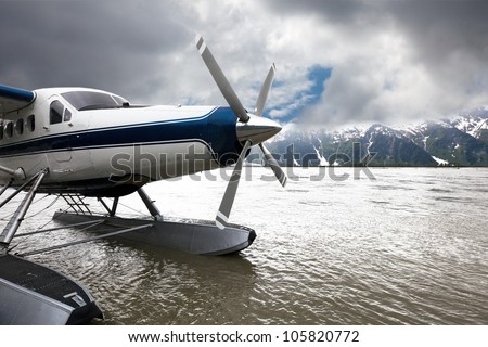 Float plane or seaplane in Alaska that has landed with storm clouds overhead.  The blue and white plane flew from Juneau.