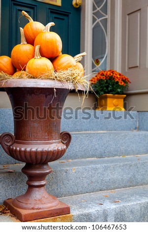 Pumpkins arranged in a large urn by the front door.  Seasonal display for fall.