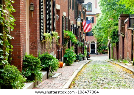 Cobblestone street in Boston.  Historic Acorn Street in Beacon Hill, called the most picturesque street in America, with a row of vintage red brick buildings.