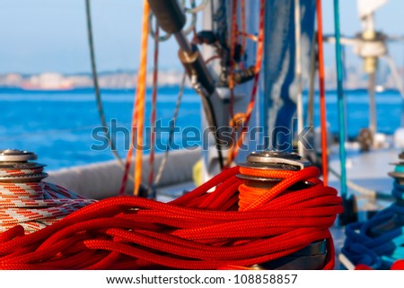 Colorful ropes on the deck of a large sailboat at sail. Selective focus on the ropes brightly lit by a setting sun.