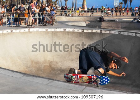 VENICE-AUG 4: A skateboarder skates sideways along the edge of a bowl while a crowd watches him at the Venice Skatepark in Venice, CA on Aug. 4, 2012.