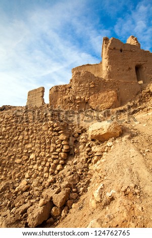 Moroccan ruins against a blue sky with clouds. Location: The remote Berber village of Aoufous, Morocco