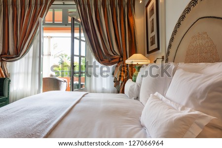 Luxury bedroom that opens with French doors onto a terrace.  King bed with white linens and pillows.