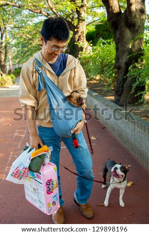 TOKYO-SEPT.20:A dog owner with one pup in a baby sling and another on a leash, carries a bag of doggie diapers in Tokyo on Sept. 20, 2009.The $10 billion pet industry in Japan caters to pampered pets.