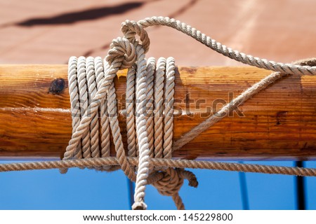 Rope, knots and wood detail on a tall ship schooner. Close up view of textures.