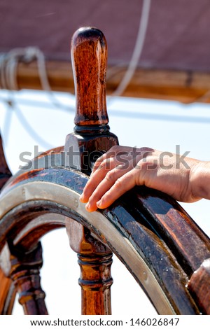Captain\'s hand on the wheel of the ship. Concept for leadership, guidance, responsibility, smooth sailing