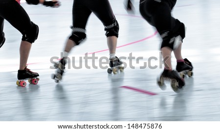 Panning action shot of skaters in a roller derby competition. Pan with motion blur.