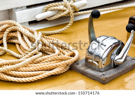 Nautical rope and chrome fittings on the deck of a vintage wooden sailboat.  Close up detail.