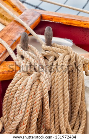 Nautical rope on a sailboat with close up view of texture detail. Coils of heavy rope tied to wooden belaying pins on a traditionally rigged schooner.