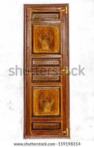 Antique Moroccan painted panel door set in a whitewashed plaster wall. Beautiful ornate design. Location: Marrakech, Morocco