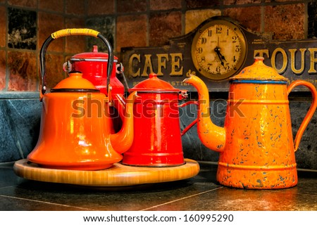 Vintage Orange And Red Enamel Kettles Displayed On A Soapstone Kitchen Counter