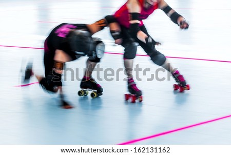 Panning action shot of roller skaters colliding during a roller derby. Pan with motion blur.