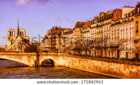Beautiful Paris in the golden glow of sunrise, featuring the Notre Dame cathedral, a bridge over the Seine and classic buildings with balconies along the river. Romantic image.
