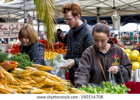 OAKLAND, CA - JAN. 11, 2014: Shoppers select fresh produce at the Grand Lake Farmers Market, open Saturdays year around and one of the largest in the region. More than 100 farmers participate.