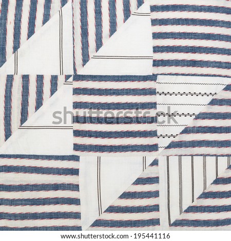 Vintage quilt square stitched by hand. Blue and white stripes with red accents. Top view close up.